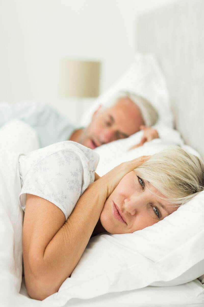 Mann schnarcht – Frau liegt wach und hält sich die Ohren zu